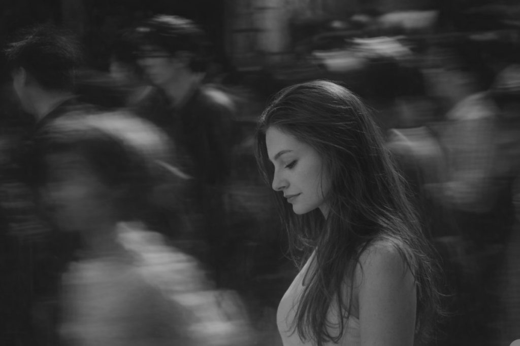 A person standing still and grounded while a blurred crowd rushes around them, symbolizing anxiety, overwhelm, and the desire to slow down.