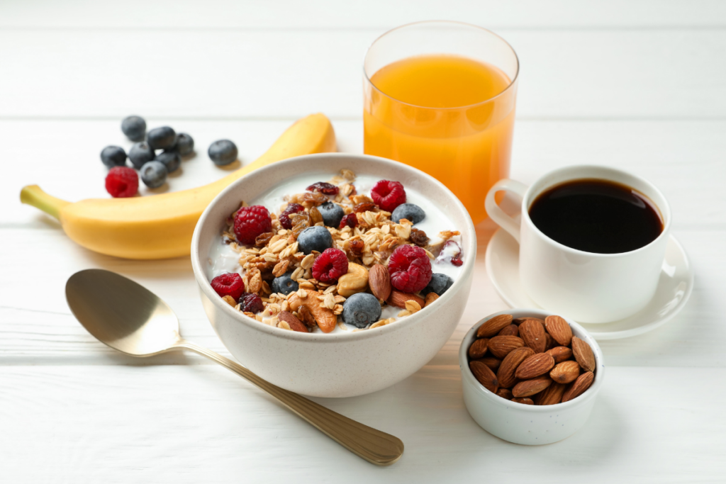 A bright flatlay of a healthy breakfast with yogurt, granola, berries, nuts, coffee, and orange juice, part of a nourishing Sunday morning routine.