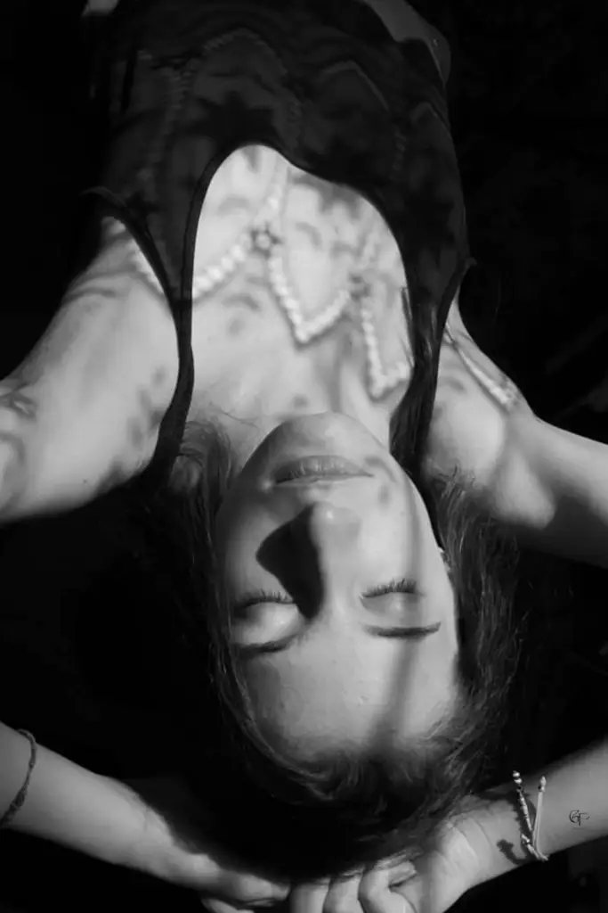  Black‑and‑white photo of a woman lying down with patterned shadows across her face, symbolizing hidden signs of burnout and emotional exhaustion.