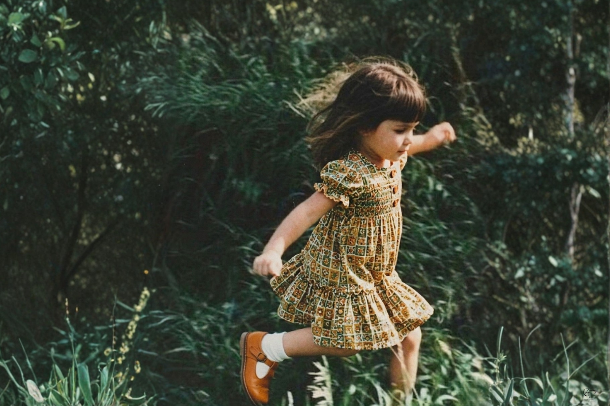 A young child jumps joyfully outdoors in lush greenery, symbolizing inner child healing and the emotional work behind reparenting journaling prompts.