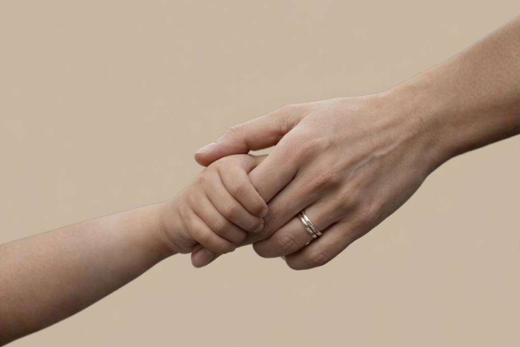 Adult and child holding hands against a neutral background, symbolizing safety, reassurance, and parental support for a Child Bullied at School.