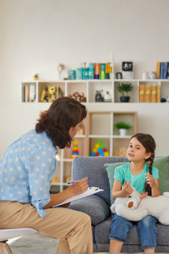 Child holding a stuffed animal while talking to a therapist in a calm office setting, illustrating emotional support for kids experiencing bullying or social exclusion.
